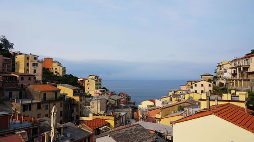 Houses in town by sea against sky