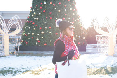 Woman standing by christmas tree during winter