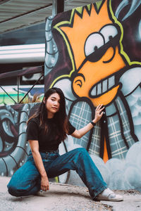 Full length of young woman sitting on wall