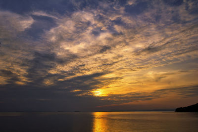 Scenic view of sea against dramatic sky during sunset