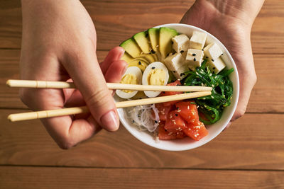 High angle view of person hand holding bowl of table