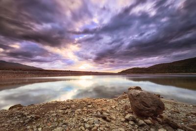 Scenic view of dramatic sky over lake during sunset