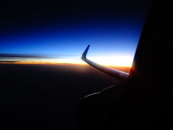 Silhouette airplane flying against clear sky at sunset