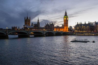 Westminster bridge over thames river against sky in city at dusk