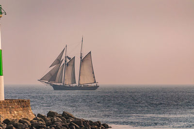 Sailboat sailing on sea against clear sky during sunset