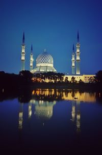 Reflection of illuminated mosque in lake at night