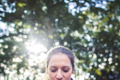 Close-up portrait of young woman against trees