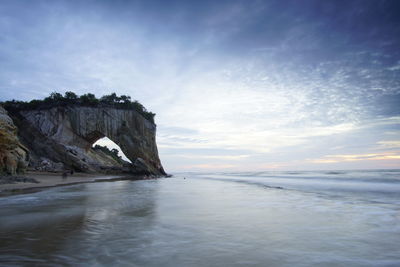 Rock formation in sea against sky during sunset