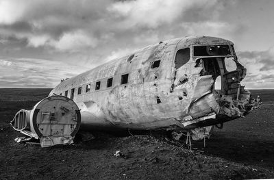 Abandoned airplane on sand against sky