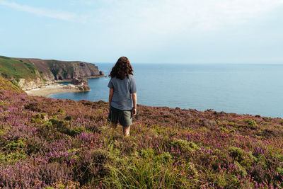 Rear view of teenage girl looking at sea against sky