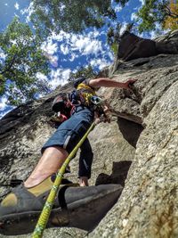 Low angle view of young man climbing on rocky mountain