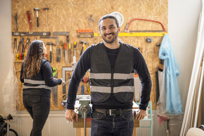 Portrait of happy male technician leaning on table at recycling center