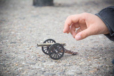 Cropped hand with toy cannon on road