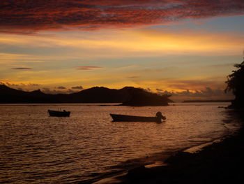 Silhouette boats in sea against sky during sunset