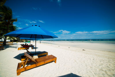 Lifeguard hut on beach against blue sky