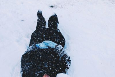 Low section of man lying on snow covered field