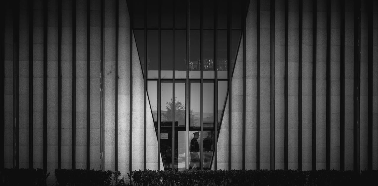 MAN SEEN THROUGH BLINDS WINDOW