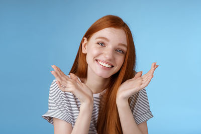 Smiling young woman gesturing against blue background