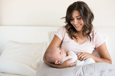 Smiling mother looking at son while sitting on sofa at home