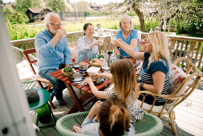 Multi-generational family toasting glasses while sitting at table in patio