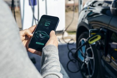 Man checking car charging status on smart phone