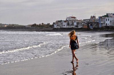 Rear view of woman standing on beach
