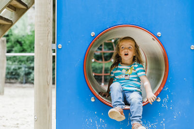 Cute girl sitting on outdoor play equipment