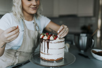 Woman in kitchen decorating cake