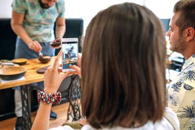 Midsection of woman using smart phone while sitting on table