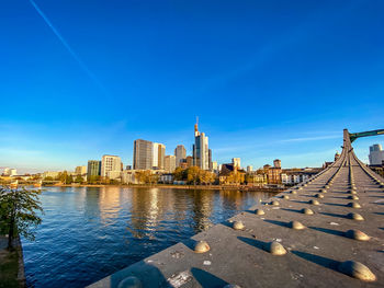 River by buildings against blue sky