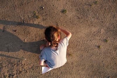 Rear view of woman sitting on land