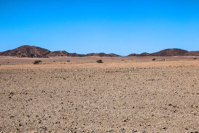 Scenic view of desert against clear blue sky