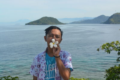 Portrait of man standing in sea against mountains