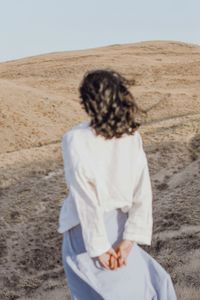 Rear view of woman with umbrella walking on desert