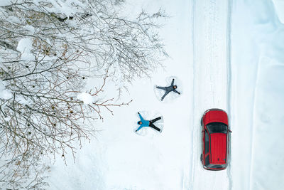 Couple making snow angels in winter landscape