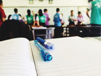 Close-up of open book with pens on table