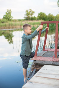 Side view of boy on pier over lake