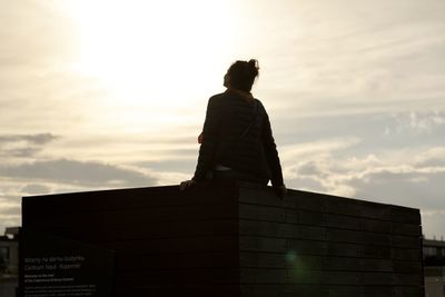 Low angle view of man sitting against sky