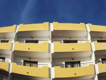 Low angle view of yellow building against blue sky