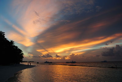 Scenic view of sea against dramatic sky during sunset