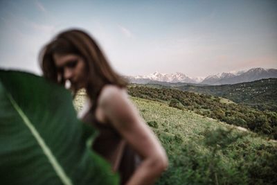 Woman with arms raised on mountain against sky