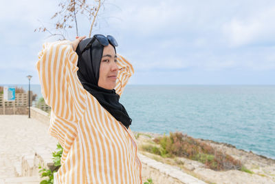 Maghrebi woman with hijab and glasses relaxing near the sea