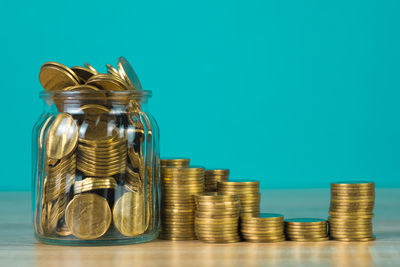 Close-up of coins in jar against blue background