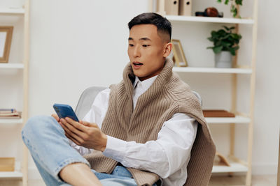 Portrait of young woman using mobile phone while sitting at home