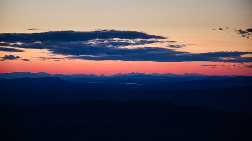 Scenic view of dramatic sky over silhouette landscape during sunset