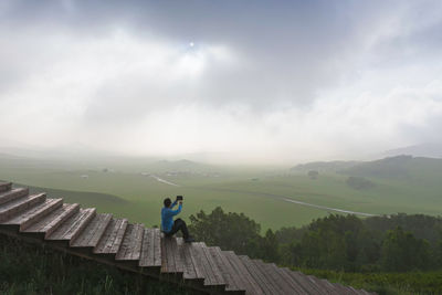 Man photographing while sitting on staircase