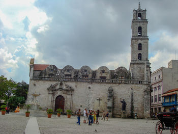 People in front of historic building against sky