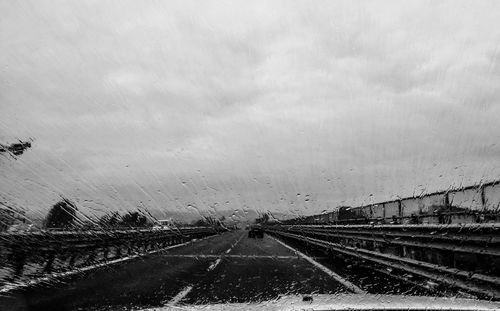 Country road against cloudy sky seen through car windshield