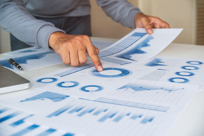 Midsection of man holding paper on table