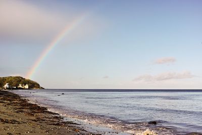 Scenic view of sea against rainbow in sky